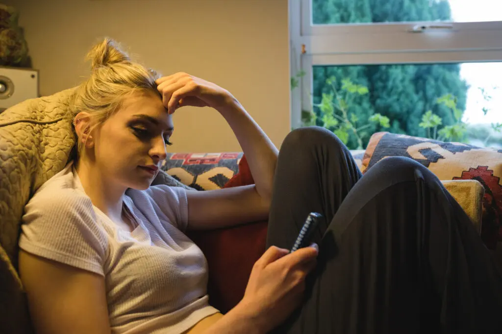 Tiener op de bank met telefoon